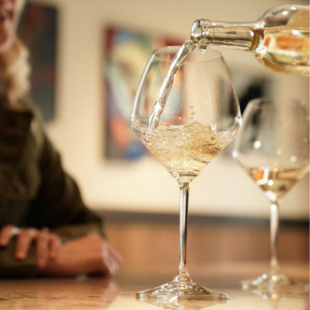 Close up of a bottle of white wine pouring into a glass