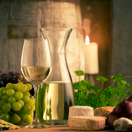 Wine glass next to a vase of wine and cheeses