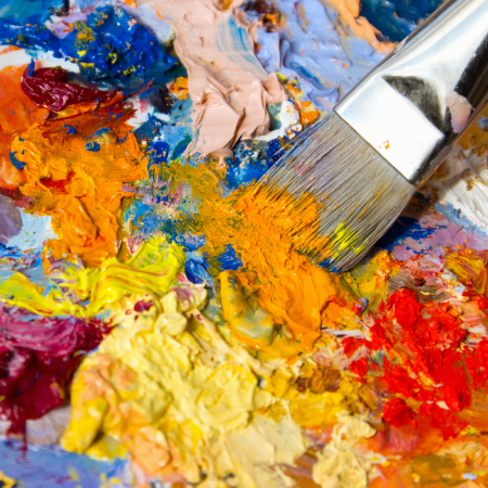 Close up of a paintbrush in yellow, orange, blue and red paint